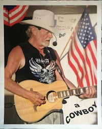 a man in a cowboy hat holding an acoustic guitar