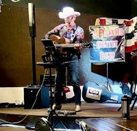 a man in a cowboy hat is playing an acoustic guitar