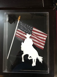 a picture of a cowboy riding a horse with an american flag