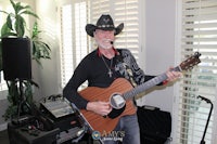a man in a cowboy hat playing an acoustic guitar